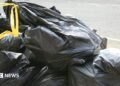 Black bin bags with yellow handles stacked on top of each other