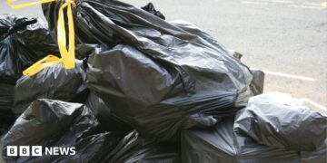 Black bin bags with yellow handles stacked on top of each other