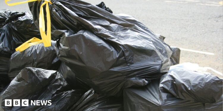 Black bin bags with yellow handles stacked on top of each other