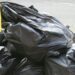 Black bin bags with yellow handles stacked on top of each other