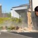 A topless man stands in the street while an earthquake damages buildings around him