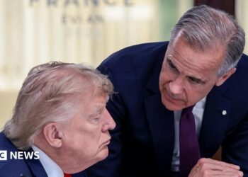 US President Donald Trump (left) speaks with Canada's Prime Minister Mark Carney during a work lunch as part of the G7 summit, in Evian, eastern France, on June 16, 2026. Trump is sitting down while Carney is standing over but leaning into the conversation.