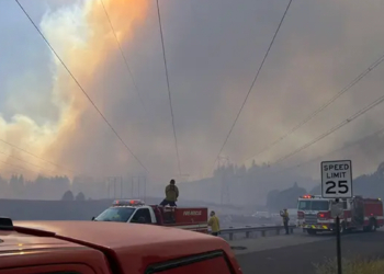 Firefighters respond beneath a massive smoke plume during the Spokane-area wildfires