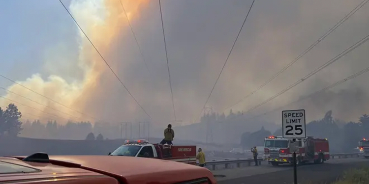 Firefighters respond beneath a massive smoke plume during the Spokane-area wildfires