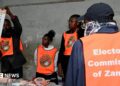 An election official displays a ballot paper as observers look on during the counting of votes after the polls closed at a polling station in Lusaka, Zambia