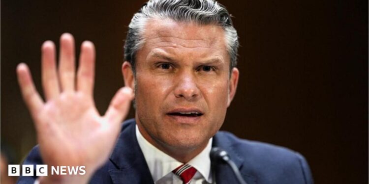 Pete Hegseth gestures by lifting his hand as he frowns