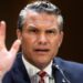 Pete Hegseth gestures by lifting his hand as he frowns