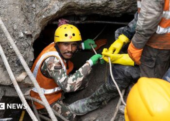 Nepalese rescuers wading through puddles of water in the Trishuli 3A tunnel