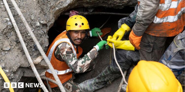 Nepalese rescuers wading through puddles of water in the Trishuli 3A tunnel
