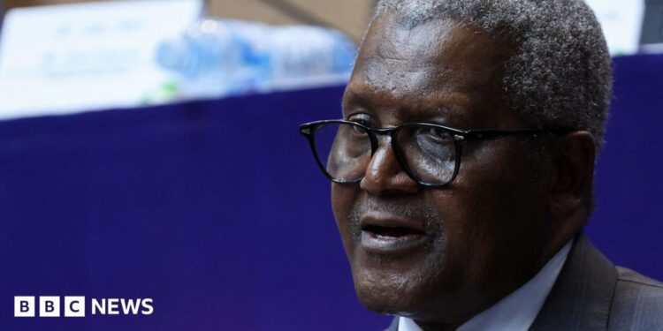 A close-up photo of Aliko Dangote. He is wearing glasses and a suit, with short, salt and pepper hair.