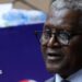 A close-up photo of Aliko Dangote. He is wearing glasses and a suit, with short, salt and pepper hair.