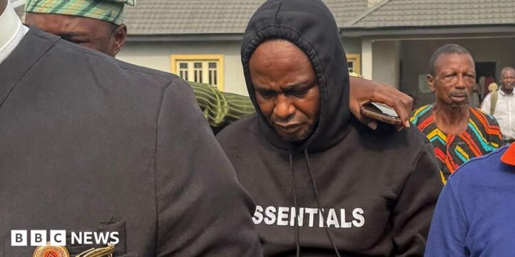 Adeniyi Mobolaji Kayode is in a black hoody with his head bowed as someone has their arm round him as he is led from court in a picture taken in January 20 this year