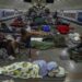 People sleeping on camping mats and sitting in fold out chairs inside a metro station during a Russian strike in Kyiv.