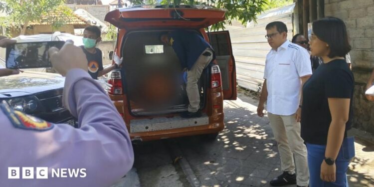 A person stands inside the rear end of an orange van while several other people stand beside the vehicle
