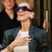 Celine Dion with a hand over her chest coming out of her hotel.