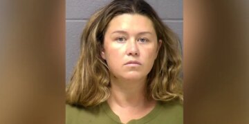 Booking mugshot of Corie A. Walsh facing forward against a gray wall wearing an olive green shirt.