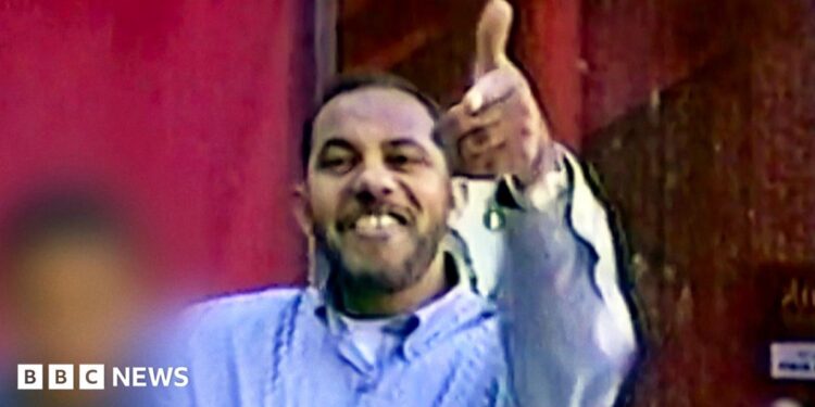 Omar al-Bayoumi in a blue shirt appears to make a gun sign with his hand