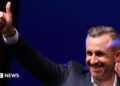 Ulrich Siegmund, leader of the AfD in the state, raises a thumbs up at the election party.