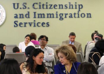 People wait inside a USCIS office as the agency changes its asylum adjudication process