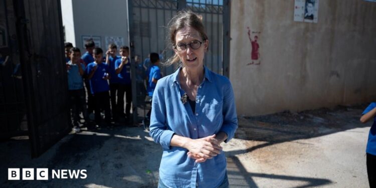 Lucy Williamson in front of children in school uniform.