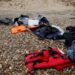 A red life jacket, bags, and other belongings left abandoned on a stony beach, following the death of at least 30 migrants on the English channel in November 2021