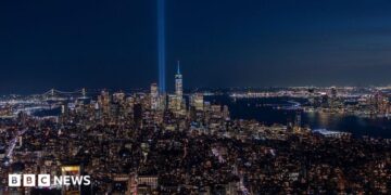 Two beams of light shooting up from the New York City skyline into the night sky, in tribute to the Twin Towers