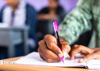 Close up shot of college student writing notes on book at classroom