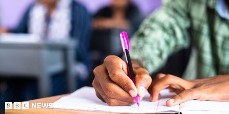 Close up shot of college student writing notes on book at classroom