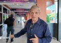 BBC correspondent Jonathan Head and a man dressed in black standing in a school corridor in Bangkok