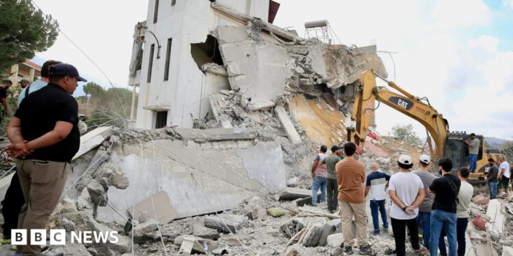 Men look at an excavator working at the site of an Israeli strike in Arab Salim, southern Lebanon