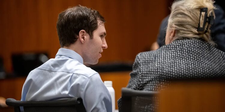 Tyler Robinson and Kathryn Nester sitting at a table with their backs to the camera in a courtroom setting.