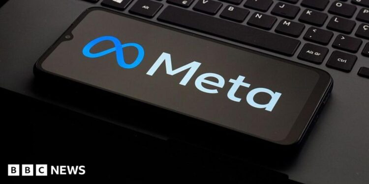 A photo of a phone kept on a laptop keyboard. The phone is displaying the logo of the company Meta