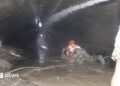 Nepalese rescuers wading through puddles of water in the Trishuli 3A tunnel