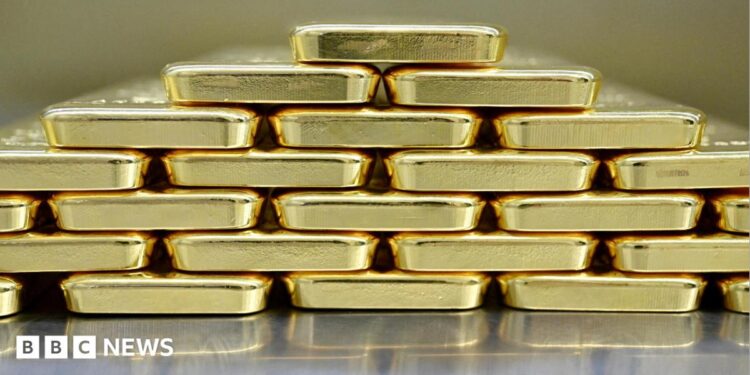 Gold bars are neatly stacked on top of each other to form a pyramid shape.