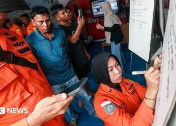 Relatives of affected passengers look on as a National Search and Rescue Agency (Basarnas) officer writes updates on a whiteboard amid ongoing rescue operations on the stricken Virgo Transport 8 ferry, at Trisakti Bandarmasih Port in Banjarmasin, South Kalimantan, on September 13, 2026.