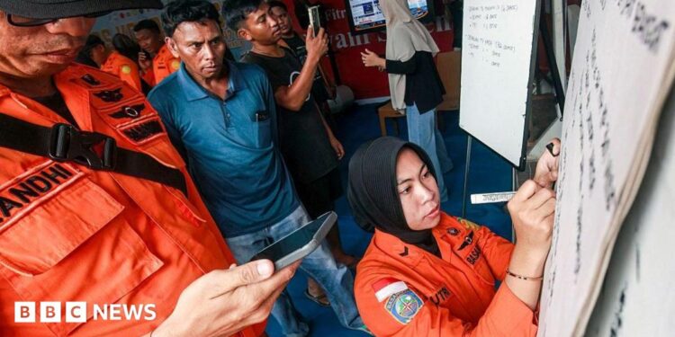 Relatives of affected passengers look on as a National Search and Rescue Agency (Basarnas) officer writes updates on a whiteboard amid ongoing rescue operations on the stricken Virgo Transport 8 ferry, at Trisakti Bandarmasih Port in Banjarmasin, South Kalimantan, on September 13, 2026.