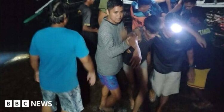 Two men helping another man off a small boat, supporting his arms as they walk away