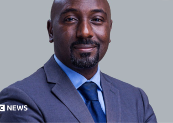 Edward Rukidi Kijanangoma wearing a dark suit and tie smiling