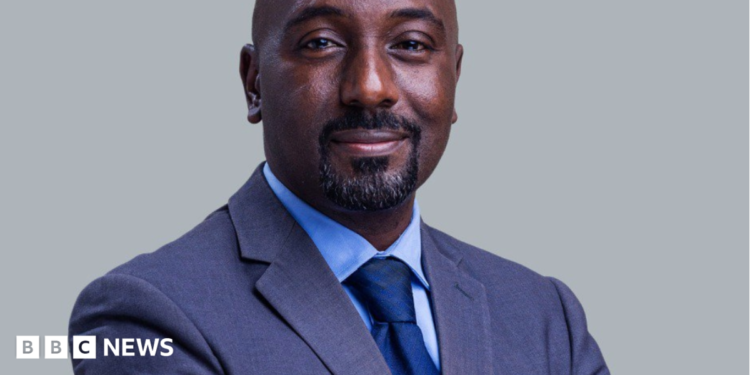 Edward Rukidi Kijanangoma wearing a dark suit and tie smiling