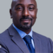 Edward Rukidi Kijanangoma wearing a dark suit and tie smiling