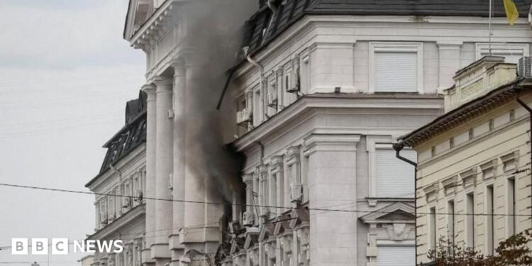 Black smoke pours from two windows in a large government building
