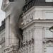 Black smoke pours from two windows in a large government building