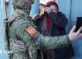 Local resident watches a video message of her relative on the smartphone of a Chechen Akhmat battalion fighter in the village of Kazachya Loknya in March 2025
