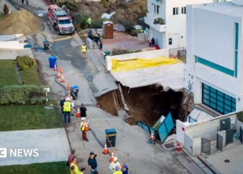Debris and warped road pictured in front of sinkhole beside white house in Malibu