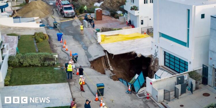 Debris and warped road pictured in front of sinkhole beside white house in Malibu