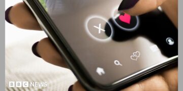 A woman with black painted nails presses a heart on a mobile phone