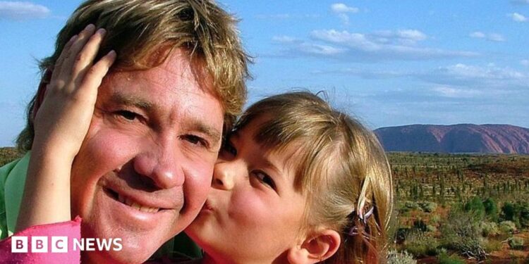 A cut of of Anthony Zurcher wearing a suit and tie in front of a red, black, grey and blue graphic background featuring the US Capitol Building