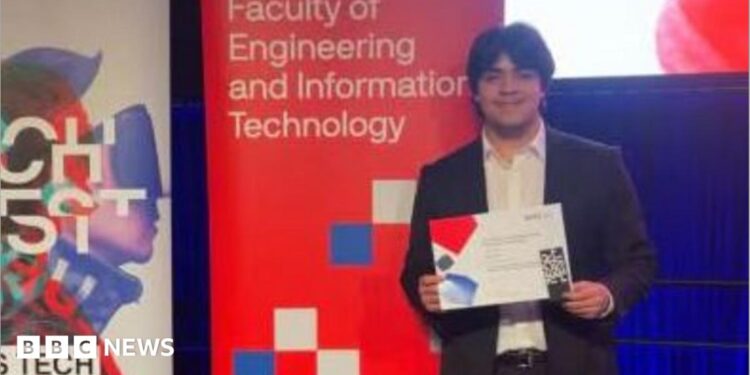 A young man in a suit holding up a certificate and standing in front of signs, one titled UTS Tech Festival and another Faculty of Engineering and Information Technology