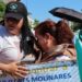 People take part in a march for peace in Culiacan, Mexico on 13 September 2026. A woman wearing a white T-shirt and a black baseball cap comforts another woman who is crying. The woman with the baseball cap is carrying a placard reading "help us find Jose Gonzalo Flores Molinares". In the background another protester is holding up another banner with the photos of missing people on it.