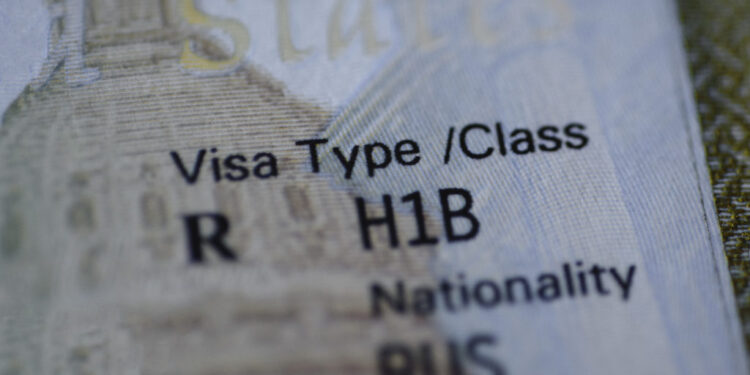 Fragment of H1B visa (for specialty workers) stamp in passport, blurred april calendar on background. H1B visa program dea...